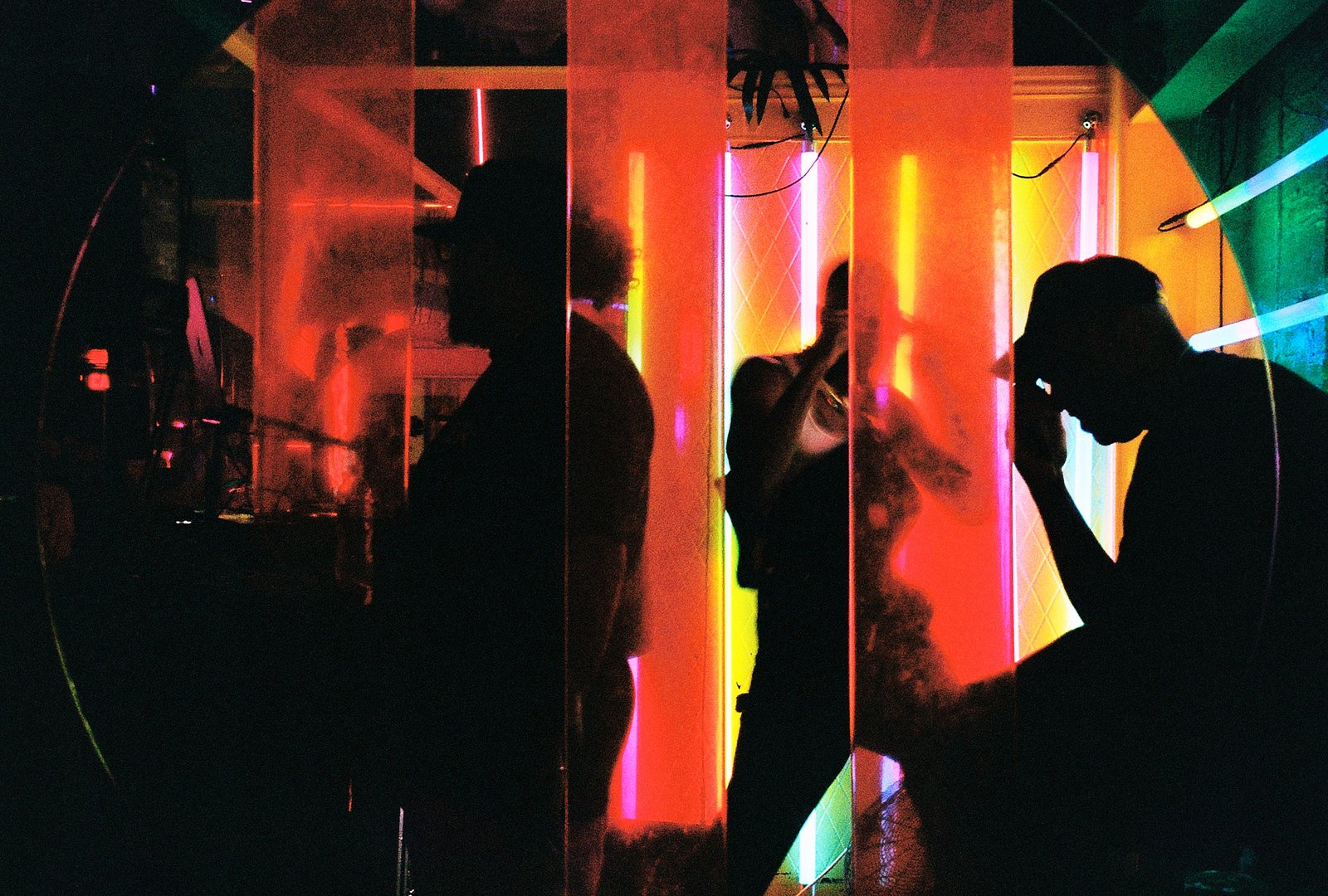 Silhouetted figures against neon red and green lights in an Austin nightclub
